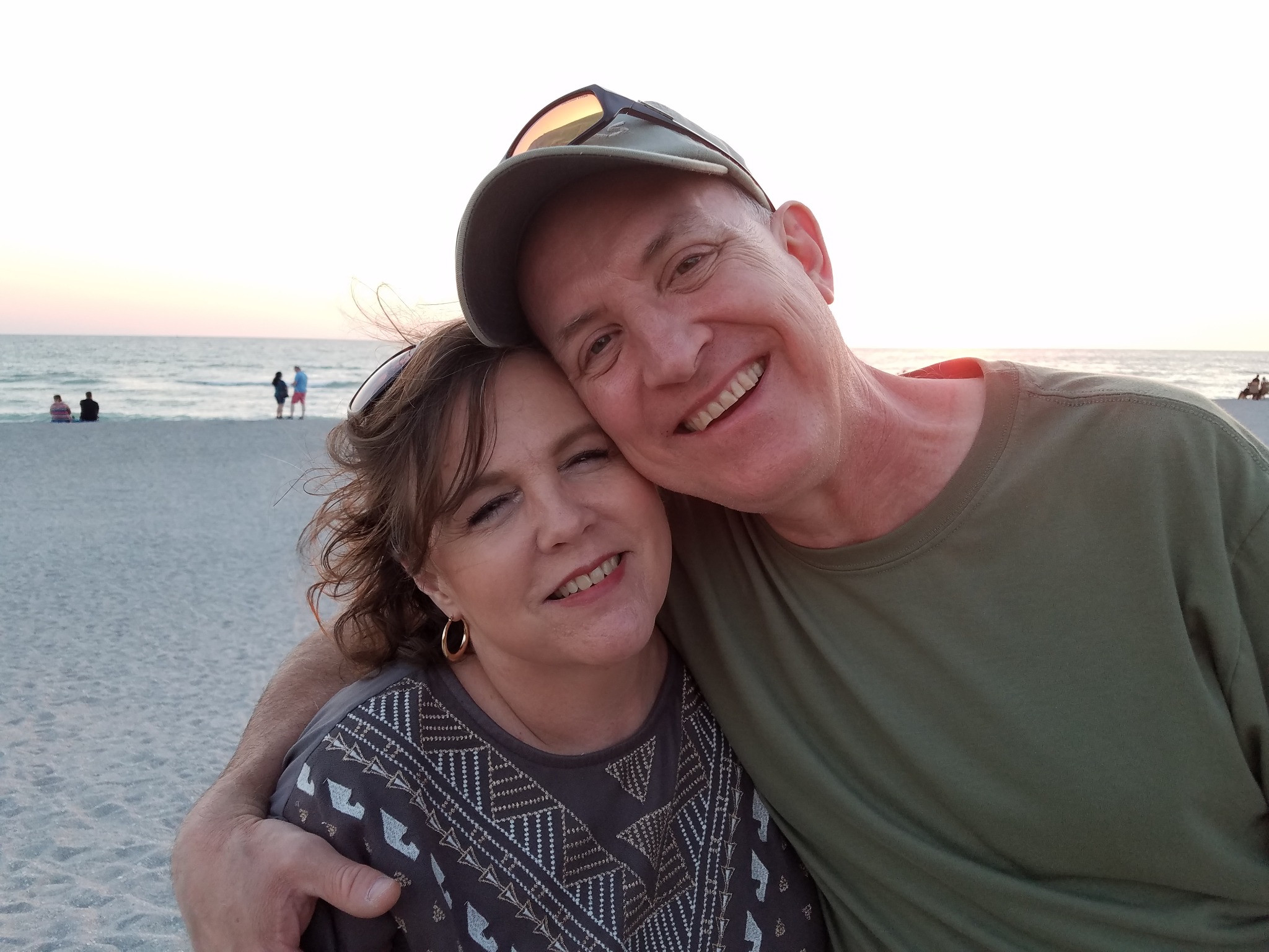 Greg and Amy smiling together at the beach.